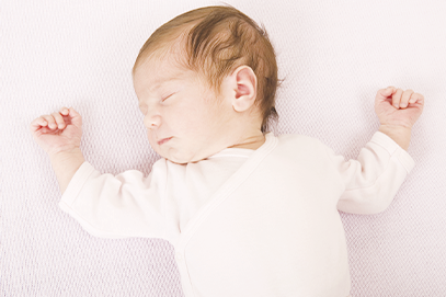 newborn baby sleeping on back on an empty firm surface