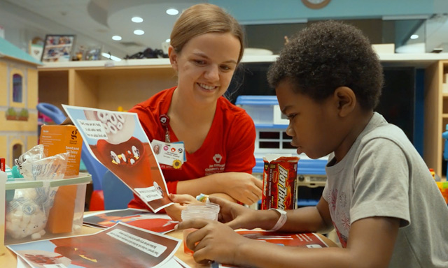 Child life specialist with patient, learning to read